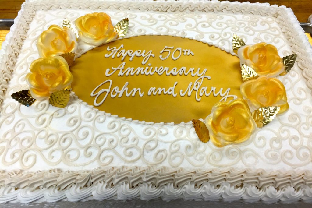 Large anniversary cake that reads "Happy 50ths anniversary John and Mary"