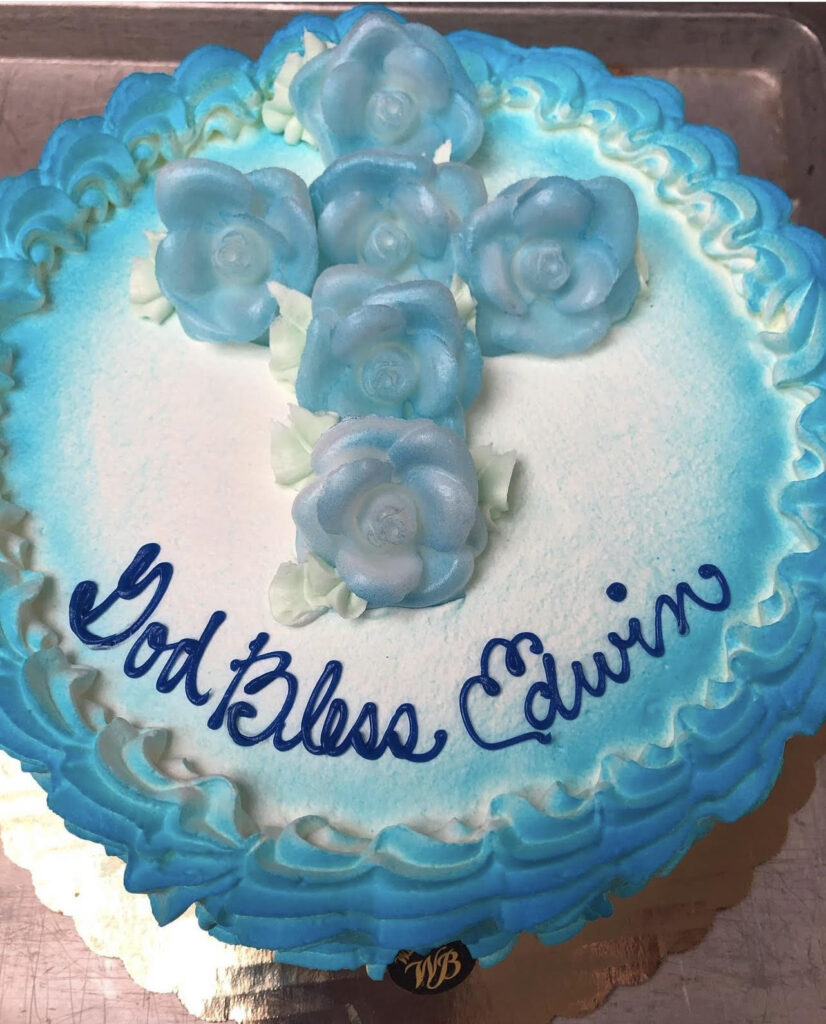 White and blue communion cake that reads "God Bless Edwin"