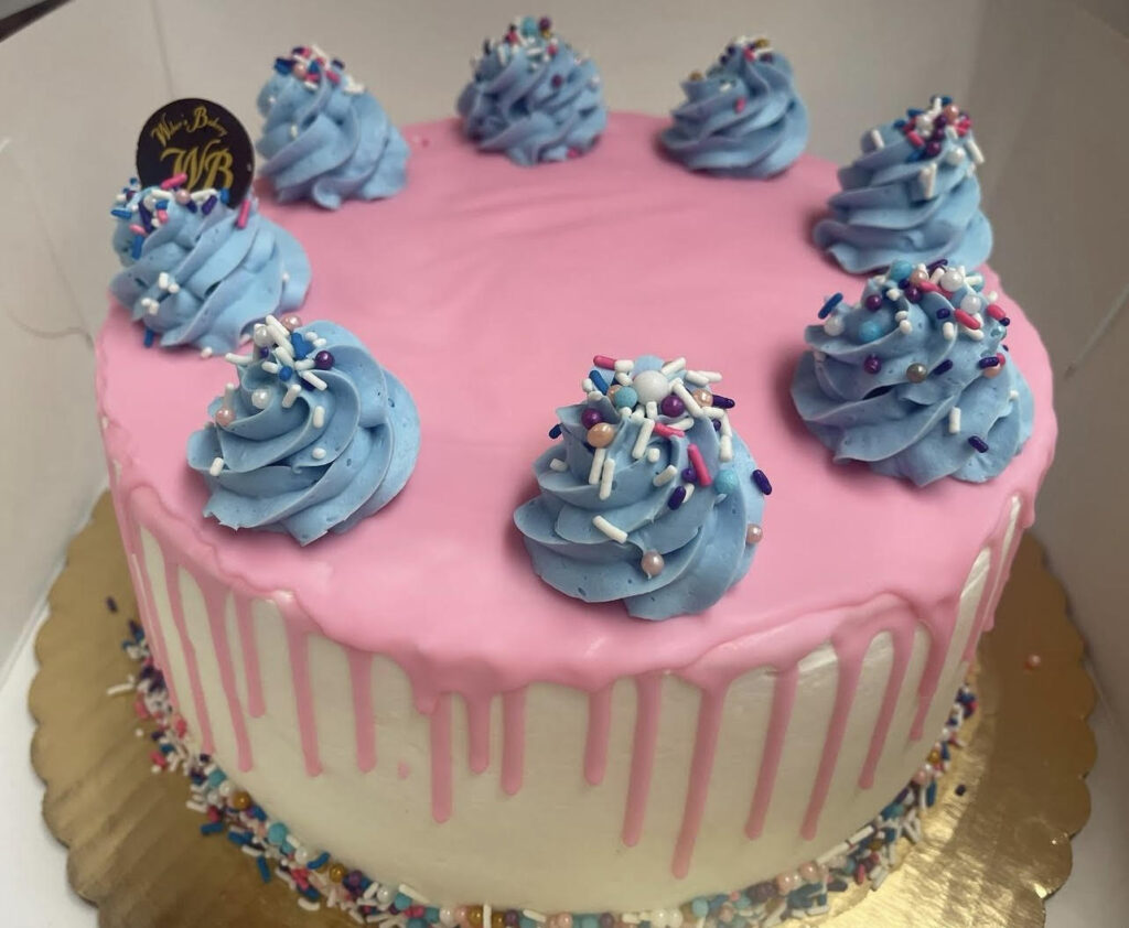 Pink drip cake with blue frosting swirls