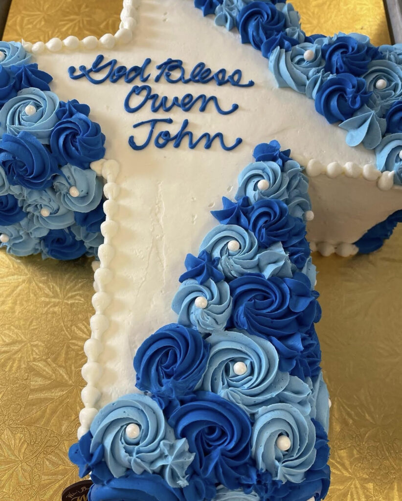 White and blue religious cake that reads "God bless Owen John"